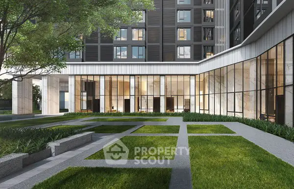 Modern building exterior with lush green courtyard and large windows.