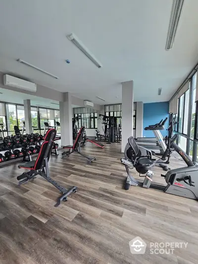 Modern gym with state-of-the-art equipment and large windows in luxury apartment complex