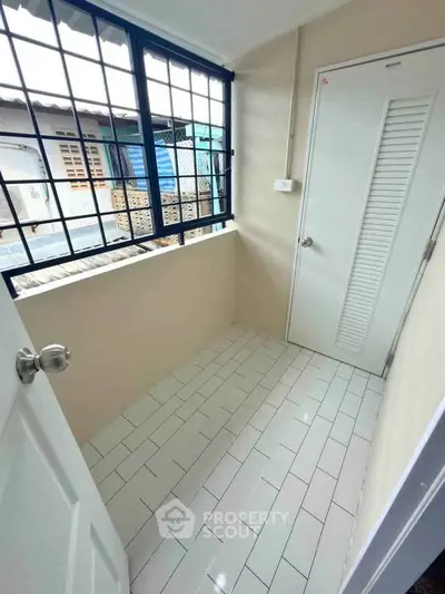 Cozy small balcony with tiled floor and window view, perfect for relaxation.