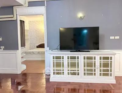 Spacious living room with elegant TV cabinet and glimpse of cozy bedroom