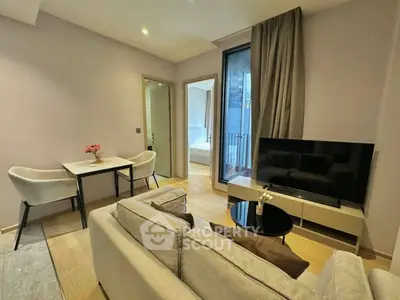 Modern living room with cozy seating and large TV, adjacent to dining area and bedroom access.