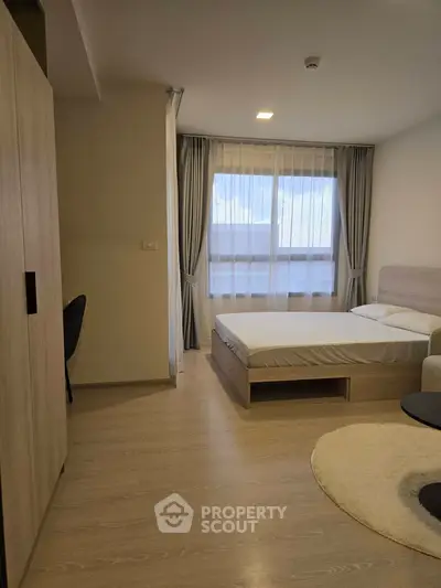 Modern bedroom with natural light and minimalist decor, featuring a cozy bed and stylish furnishings.