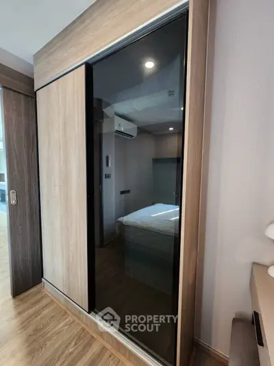 Modern bedroom with sleek sliding wardrobe and wooden flooring