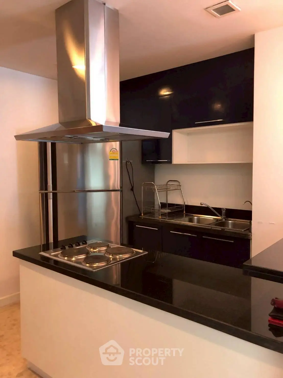 Modern kitchen with sleek black countertops and stainless steel appliances in a stylish apartment.
