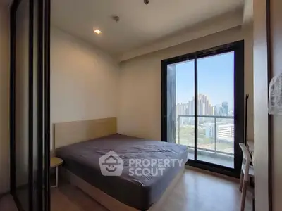 Modern bedroom with city view and balcony access in high-rise apartment