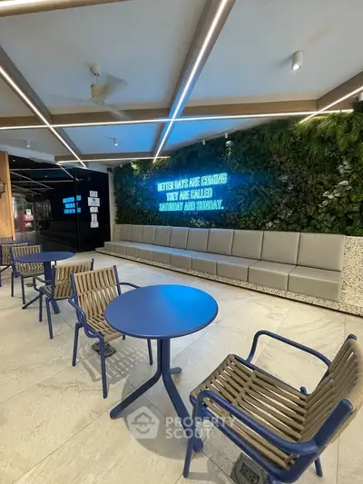 Modern building entrance with stylish seating and neon sign, perfect for relaxation.
