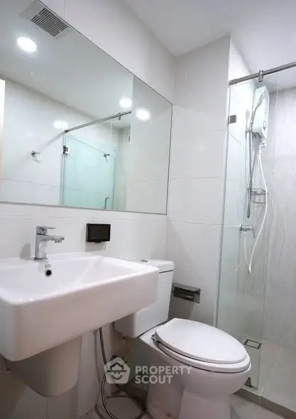 Modern bathroom with sleek fixtures and glass shower enclosure in a contemporary apartment.