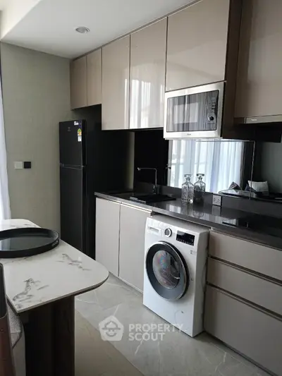 Modern kitchen with sleek cabinetry, built-in microwave, and washing machine in stylish apartment.