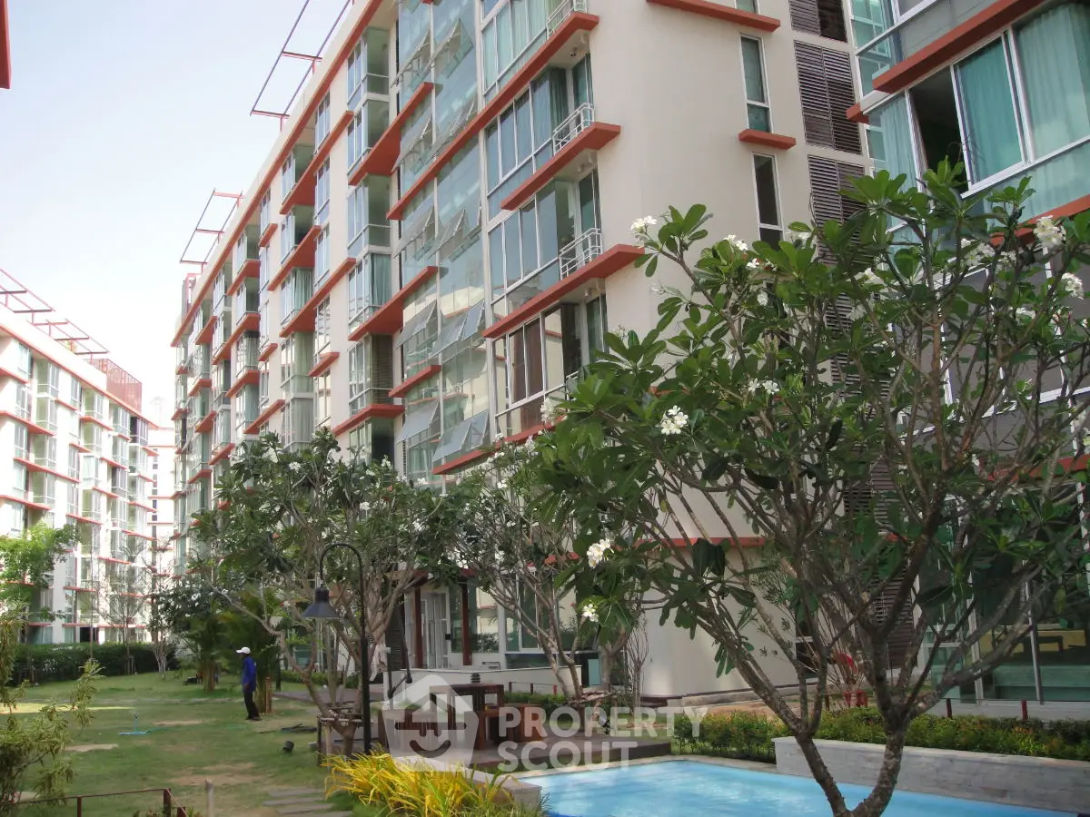 Modern apartment complex with lush garden and pool area, showcasing contemporary architecture and outdoor amenities.
