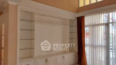 Spacious living room with built-in shelving and large windows for natural light.