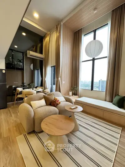 Modern living room with high ceilings and large windows offering city views.