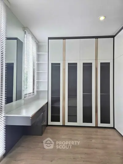 Modern bedroom with sleek built-in wardrobe and large window for natural light.