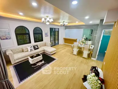 Luxurious living room with elegant chandelier and spacious dining area in modern home.