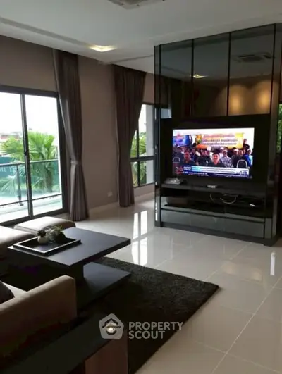 Modern living room with large windows and sleek TV setup, perfect for relaxation.
