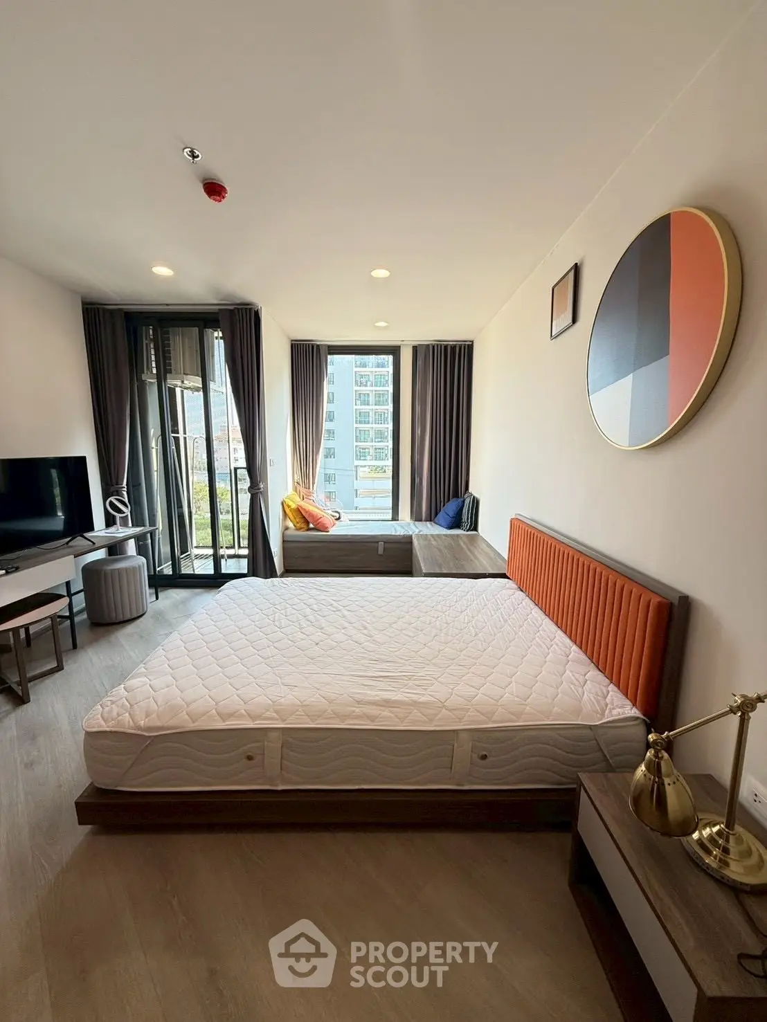 Modern bedroom with large window and stylish decor in a high-rise apartment.