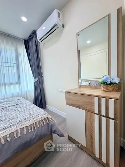 Cozy bedroom with modern decor and air conditioning, featuring a stylish dresser and large window.