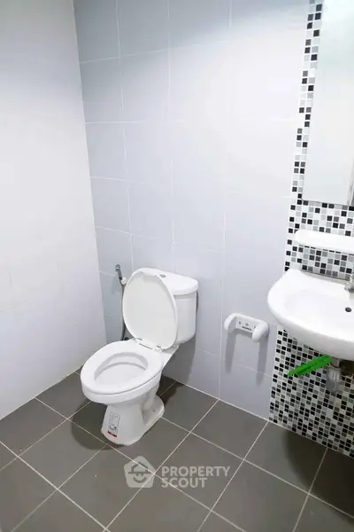 Modern bathroom with sleek white tiles and mosaic accent wall