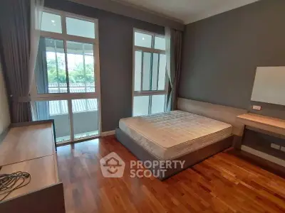 Spacious bedroom with large windows and wooden flooring in modern apartment