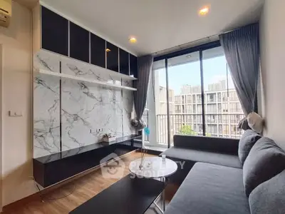 Modern living room with marble accent wall and large windows in urban apartment.