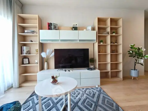 Modern living room with stylish shelving and large TV, featuring elegant decor and natural light.