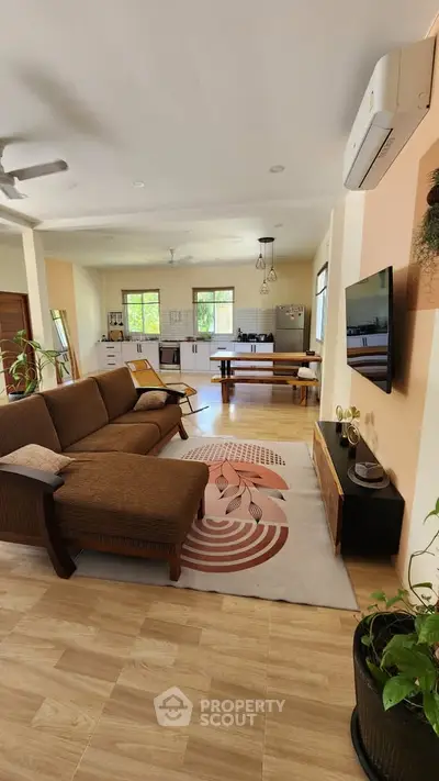 Spacious open-plan living room with modern decor and natural light, featuring a cozy sofa and stylish kitchen area.