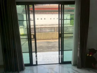 Spacious living room with sliding glass doors opening to a serene outdoor view.