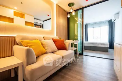 Modern living room with cozy sofa and vibrant pillows, open layout leading to a bright bedroom.