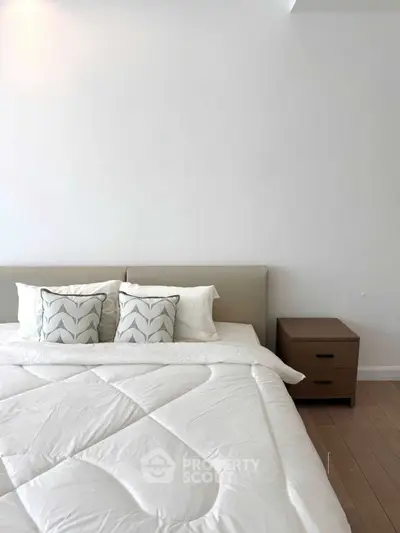 Modern bedroom with stylish bedding and wooden nightstand, perfect for a cozy retreat.