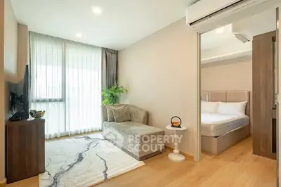 Modern living room with cozy sofa and adjacent bedroom in open layout apartment.