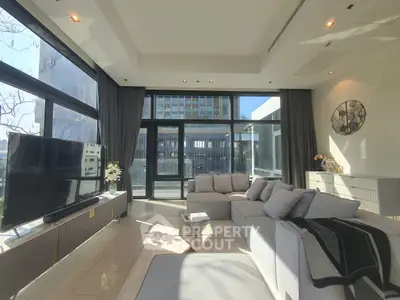 Luxurious modern living room with large windows and elegant decor in a high-rise apartment.