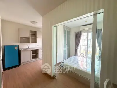 Modern studio apartment with open layout, featuring a compact kitchen and bright bedroom with balcony view.