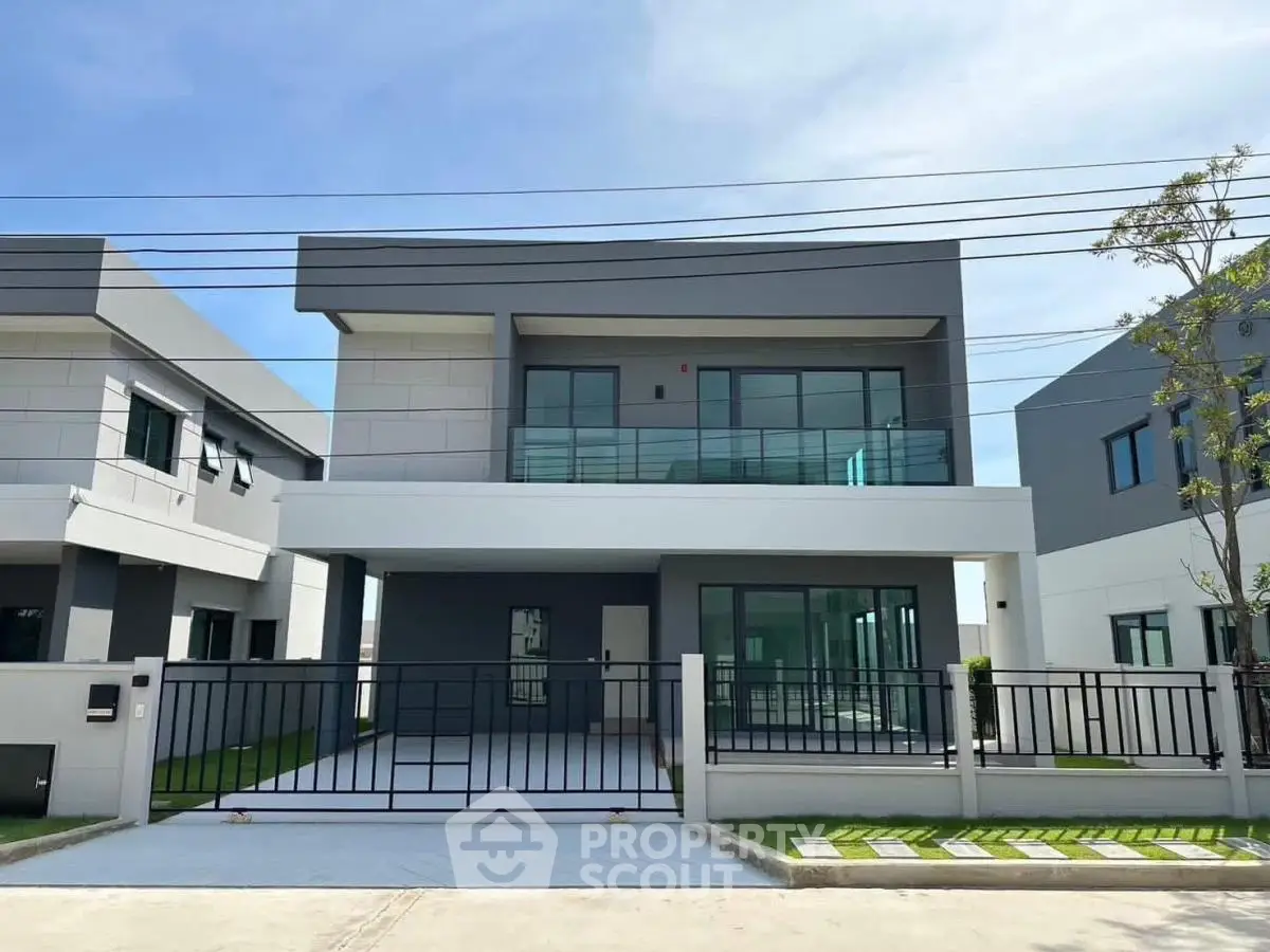 Modern two-story house with sleek design and spacious driveway in a suburban neighborhood.