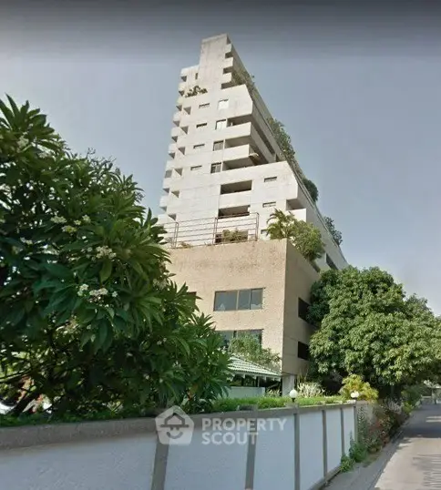 Modern multi-story building with lush greenery and contemporary design.