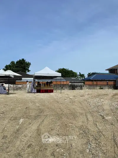 Vacant land plot with tents set up for a ceremony, potential for development.
