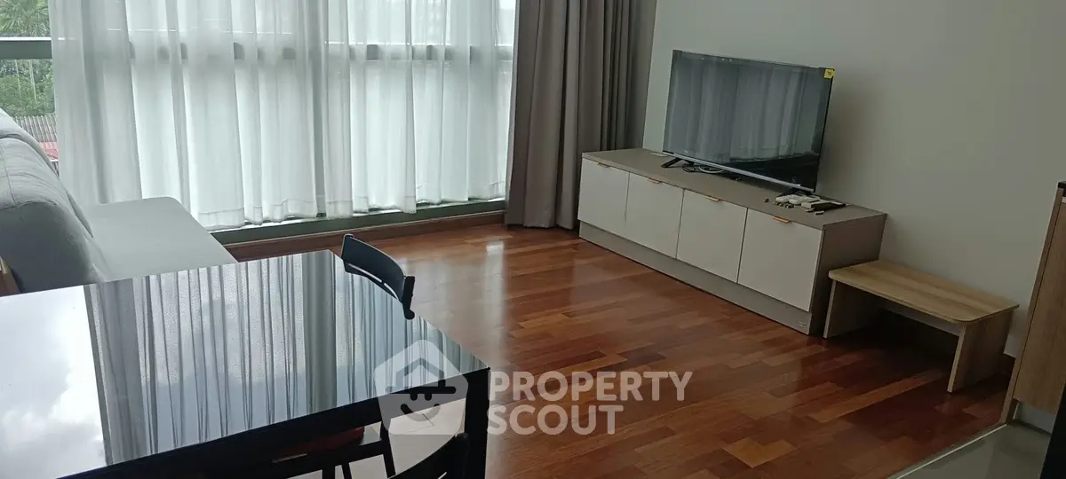 Modern living room with hardwood floors, large windows, and sleek furniture.