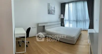 Spacious modern bedroom with large window and wooden flooring