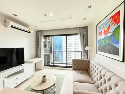 Modern living room with balcony view in high-rise apartment, featuring stylish furniture and vibrant artwork.