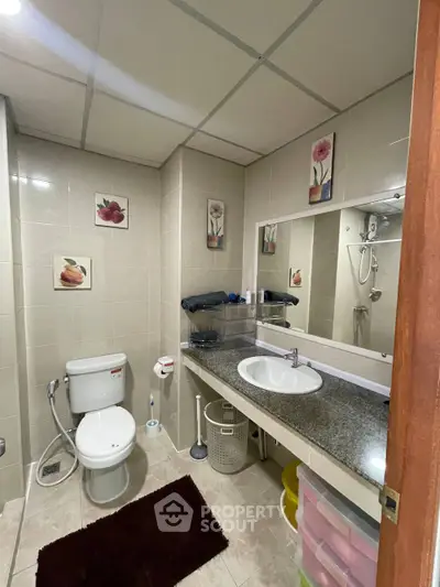 Spacious bathroom with modern fixtures and elegant decor, featuring a large mirror and ample storage space.