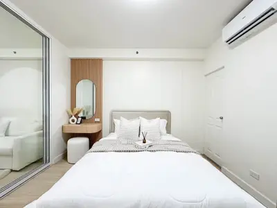 Modern bedroom with stylish decor, mirrored closet, and air conditioning unit.