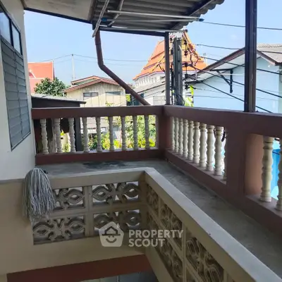 Charming balcony with traditional railing and scenic neighborhood view.
