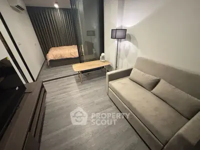 Modern studio apartment with cozy living area and bedroom, featuring sleek flooring and contemporary furnishings.