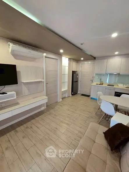 Modern open-plan living room with kitchen, featuring sleek furniture and wooden flooring.