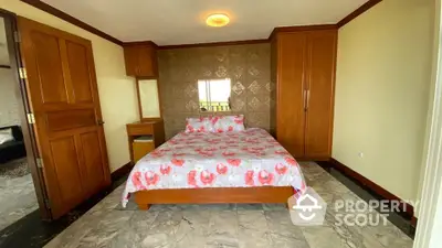 Cozy bedroom with floral bedding and wooden furniture, featuring elegant tiled accent wall.