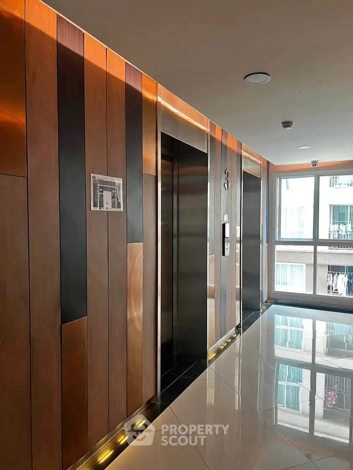 Modern building elevator lobby with sleek wood paneling and polished floors.