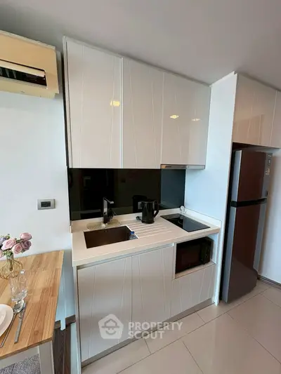 Modern compact kitchen with sleek cabinetry and appliances in a stylish apartment.