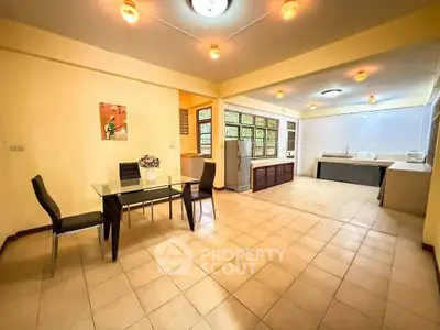 Spacious open-layout kitchen and dining area with modern lighting and tiled flooring.