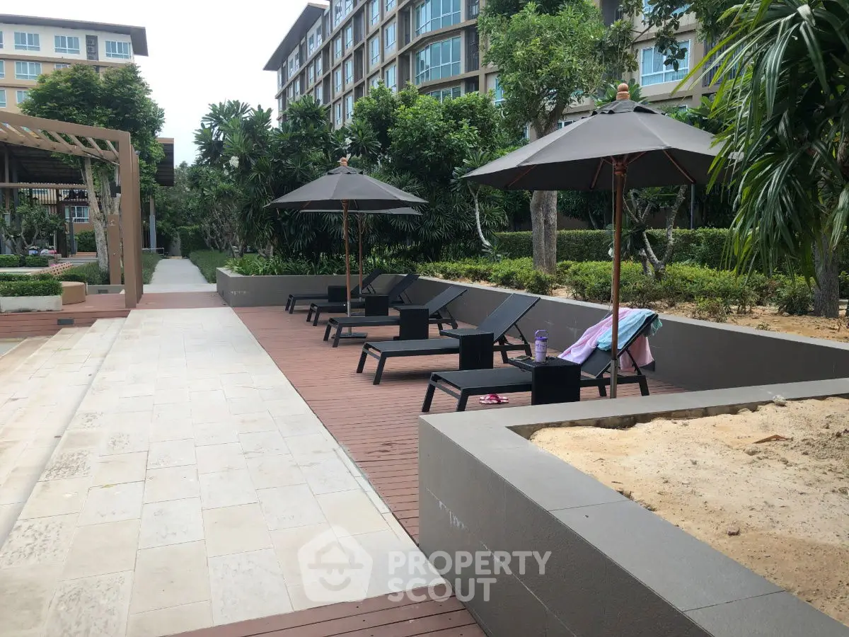 Luxurious poolside area with sun loungers and umbrellas in modern residential complex.