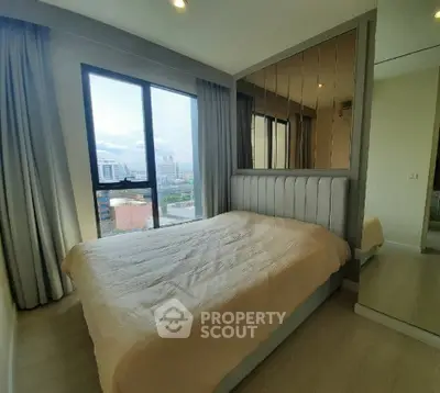 Modern bedroom with large window offering city view and stylish mirrored headboard.