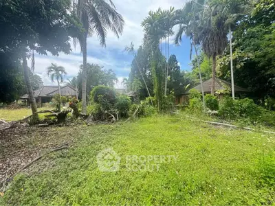 Lush tropical garden with palm trees and traditional houses, perfect for serene living.