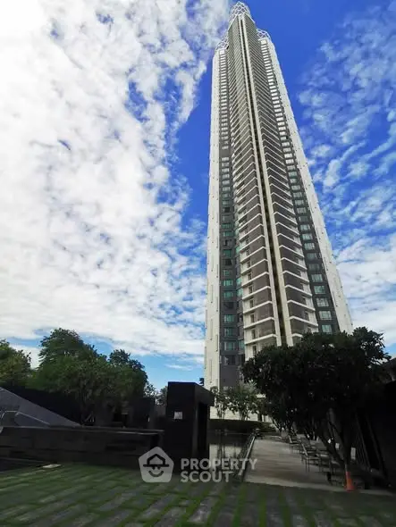 Stunning high-rise building with lush greenery and blue sky backdrop.